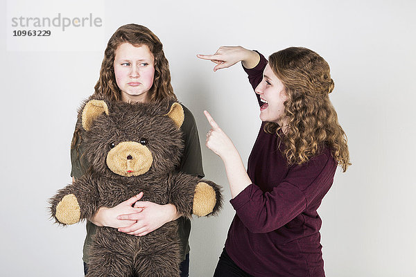 Studioaufnahme einer Freundin  die sich über eine andere Freundin lustig macht  die ihren Teddybär hält; Alberta  Kanada'.