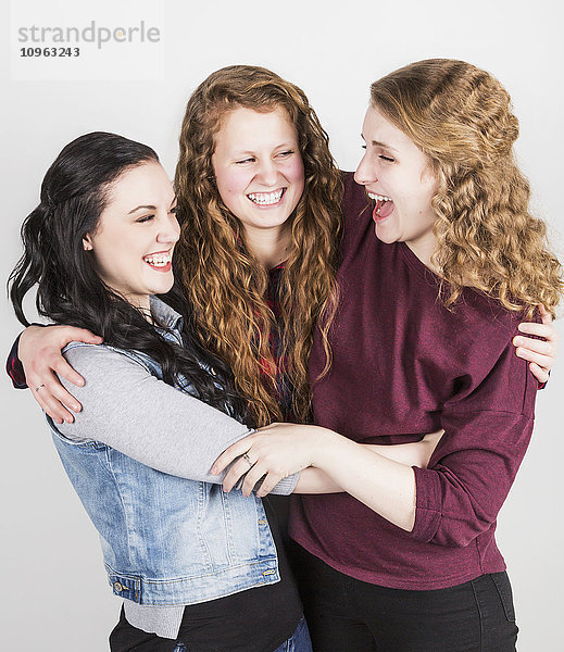 Porträt von drei jungen Frauen  die sich umarmen  auf weißem Hintergrund; Alberta  Kanada'.