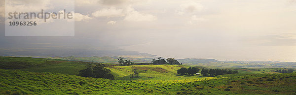 Ansicht einer Ranch auf der Big Island mit dem Pazifischen Ozean und einem teilweise bewölkten Himmel dahinter; Waimea  Insel Hawaii  Hawaii  Vereinigte Staaten von Amerika'.
