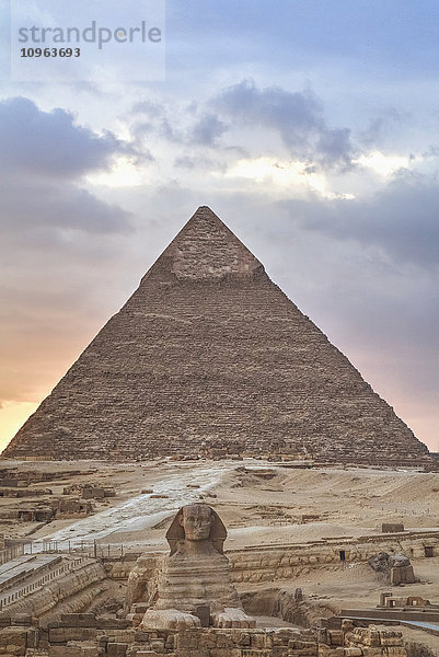 Sonnenuntergang  Sphinx (Vordergrund)  Chephren-Pyramide (Hintergrund)  Die Pyramiden von Gizeh; Gizeh  Ägypten'.