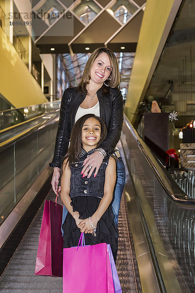 Junge Mutter und ihre Tochter benutzen eine Rolltreppe in einem Einkaufszentrum; St. Albert  Alberta  Kanada'.
