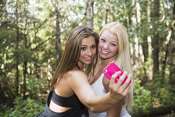 Zwei Freundinnen posieren für ein gemeinsames Selfie in einem Park; Edmonton  Alberta  Kanada'.