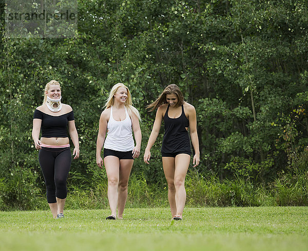 Drei junge Turnerinnen gehen in einem Park spazieren  nachdem sie ihre Übungen gemacht haben; Edmonton  Alberta  Kanada'.