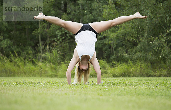 Junge Turnerin beim Üben des Handstand-Spagats im Freien in einem Park; Edmonton  Alberta  Kanada'.