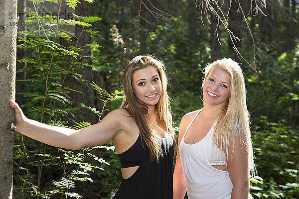Zwei Freundinnen posieren zusammen im Wald in der Sonne; Edmonton  Alberta  Kanada'.
