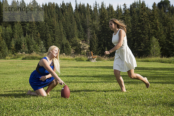 Zwei Freundinnen spielen in ihren Kleidern Fußball in einem Park; Edmonton  Alberta  Kanada'.