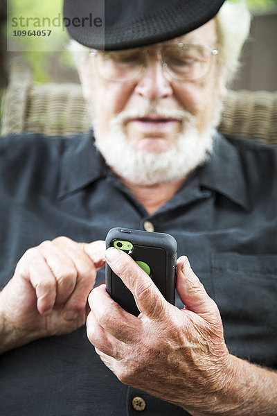 Ein älterer Mann benutzt ein Smartphone; Maple Ridge  British Columbia  Kanada'.
