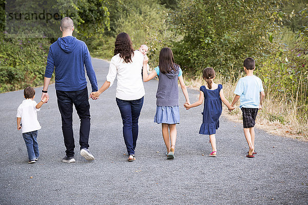 Porträt einer Familie mit fünf Kindern  die Hand in Hand einen Weg entlanggehen; Chilliwack  British Columbia  Kanada'.