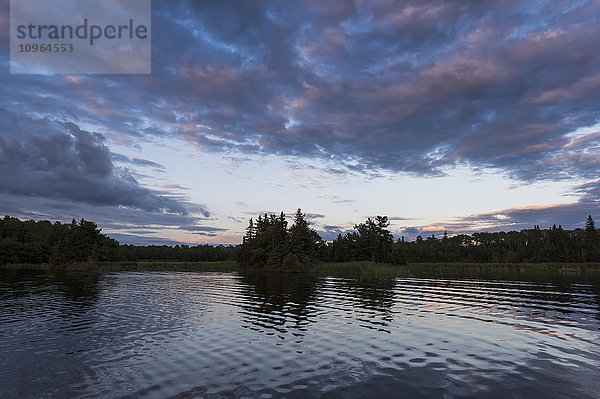 Ruhiges Wasser eines Sees bei Sonnenuntergang; Lake of the Woods  Ontario  Kanada'.