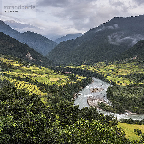 Ein Fluss  der durch ein Tal mit üppigem Ackerland fließt  umgeben von Bergen; Punakha  Bhutan'.