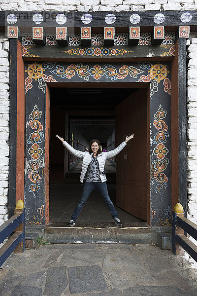 Eine Frau steht in einem verschnörkelten Portal  Rinpung Dzong; Paro  Bhutan'.