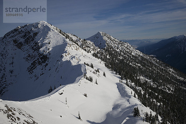 Verschneiter Berghang mit blauem Himmel und Blick auf eine Bergkette; Kicking Horse  British Columbia  Kanada'.