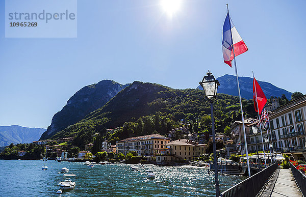 Sonnenschein auf der italienischen Flagge und Blick auf das Wasser von der Stadt Menaggio am Comer See; Menaggio  Lombardei  Italien'.