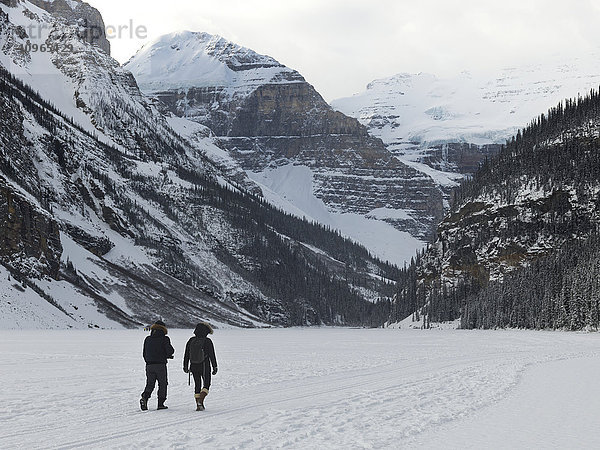 Spaziergänger auf dem zugefrorenen Lake Louise mit Blick auf die schneebedeckten Berge; Lake Louise  Alberta  Kanada'.