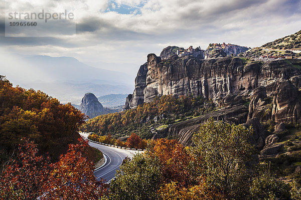 Klöster auf Felsen und eine kurvenreiche Straße im Herbstlaub; Meteora  Griechenland'.