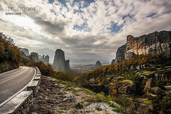 Landschaft mit zerklüfteten Felsen  Straße  Herbstlaub und dem Kloster Rousanou in der Ferne; Meteora  Griechenland'.