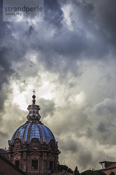 Licht bricht durch die turbulenten Wolken auf der Kuppel der Kirche Santi Luca e Martina; Rom  Italien'.