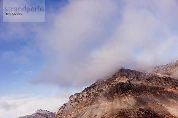 Niedrige Wolken hängen an der Spitze der erodierenden roten Klippen in der Brooks Range; Alaska  Vereinigte Staaten von Amerika'.