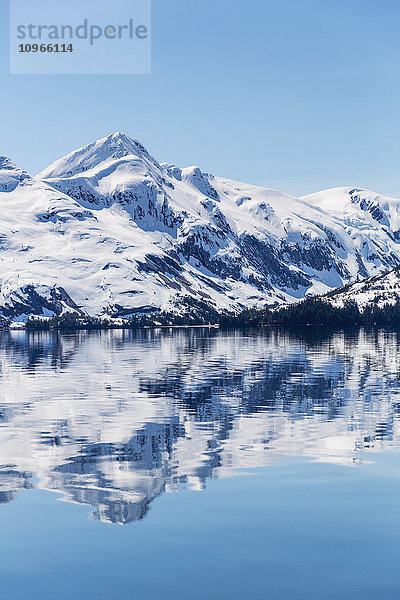 Schneebedeckte Berge spiegeln sich in den ruhigen Gewässern des Prince William Sound im Winter  Kings Bay; Alaska  Vereinigte Staaten von Amerika'.