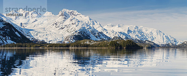 Ruhiges Meereswasser spiegelt schneebedeckte Berge an einem klaren Tag in der Kings Bay  Prince William Sound; Whittier  Alaska  Vereinigte Staaten von Amerika'.