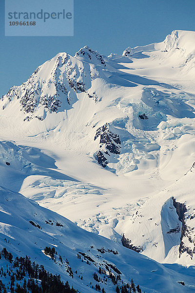 Ein Gletscher hängt in einem Tal unter zerklüfteten schneebedeckten Gipfeln in Kings Bay  Prince William Sound; Whittier  Alaska  Vereinigte Staaten von Amerika'.