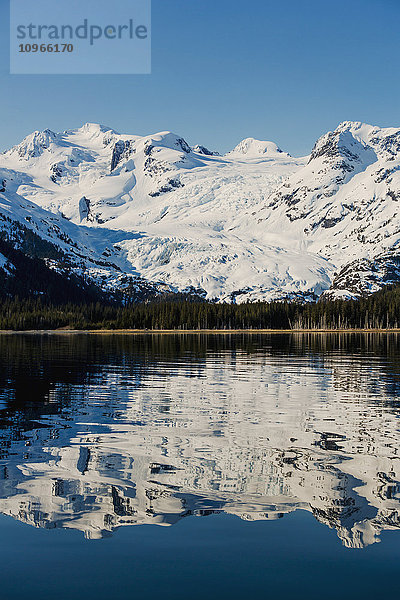 Ein Gletscher hängt in einem Tal unter zerklüfteten schneebedeckten Gipfeln in Kings Bay  Prince William Sound; Whittier  Alaska  Vereinigte Staaten von Amerika'.