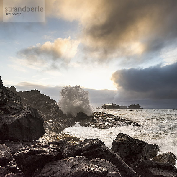 Glühende Wolken bei Sonnenuntergang mit Wellen  die gegen die Felsen schlagen; Tofino  British Columbia  Kanada'.