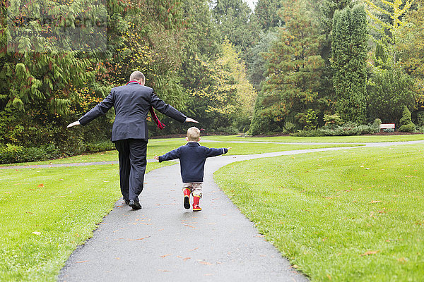 Ein Vater und sein Sohn gehen einen Weg im Bear Creek Park entlang; Surrey  British Columbia  Kanada'.