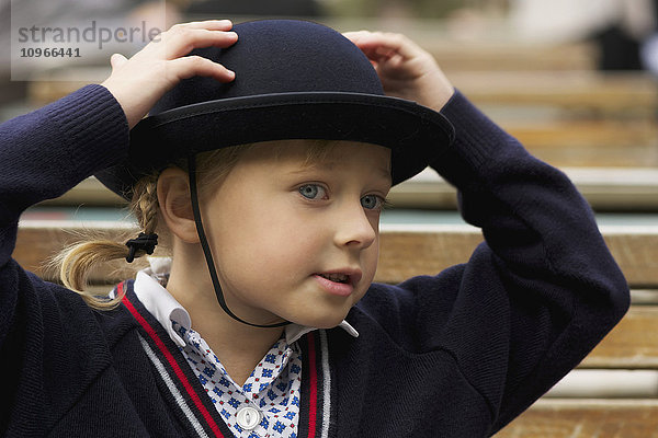 Junges Mädchen mit den Händen auf ihrem blauen Filzhut in Schuluniform; London  England'.
