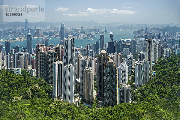 Blick auf den Victoria Harbour vom Victoria Peak aus  mit Hunderten von Wolkenkratzern an einem bewaldeten Hang; Hongkong  China'.