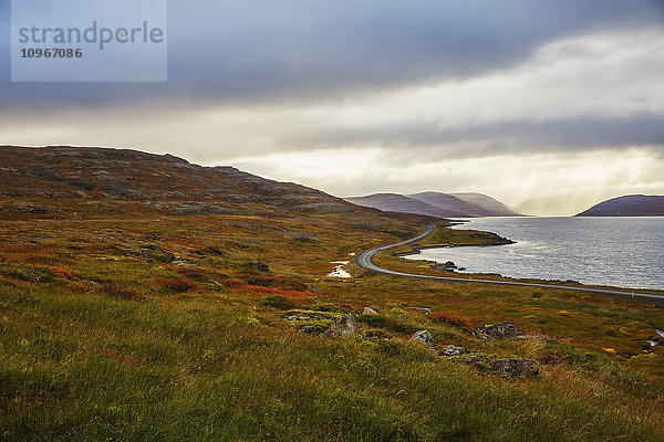 Eine Straße führt in der Ferne durch die Herbstfarben in Islands Westfjorden; Island'.
