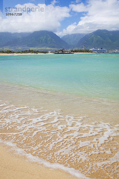 Klares türkisfarbenes Meer am Kanaha Beach mit grünen West Maui Mountains im Hintergrund; Maui  Hawaii  Vereinigte Staaten von Amerika'.