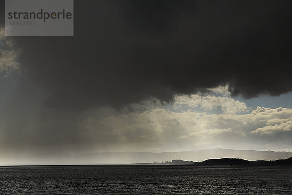Regen fällt aus bedrohlichen dunklen Wolken über dem Wasser; Otter Ferry  Schottland'.