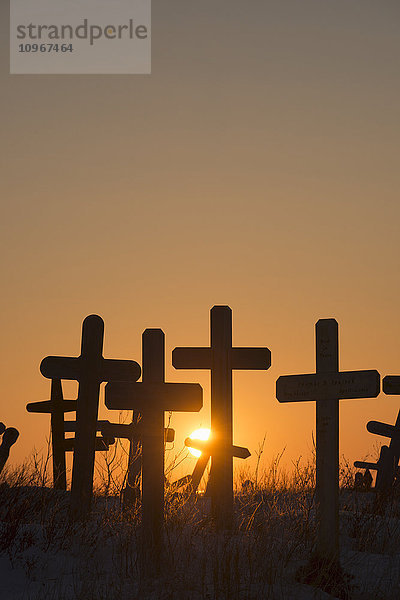 Die untergehende Sonne scheint durch die Kreuze auf dem Cemetery Hill in Kotzebue  Alaska.