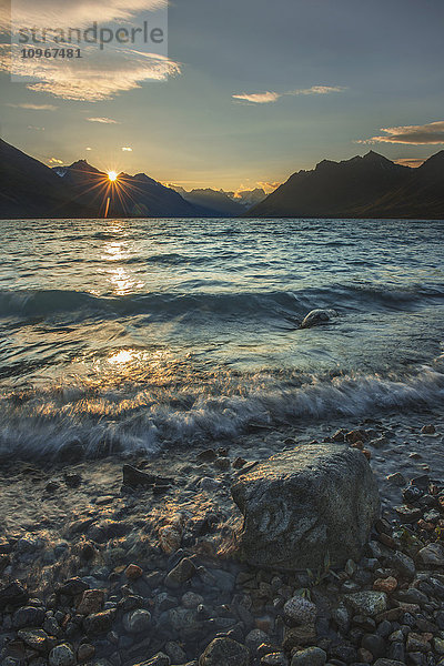 Die Sonne geht auf  während sanfte Wellen die Uferlinie des oberen Twin Lake im Lake Clark National Park & Preserve  Alaska  streifen.