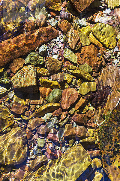 Nahaufnahme von bunten Bachsteinen unter Wasser mit Wellen im Wasser; Waterton  Alberta  Kanada'.
