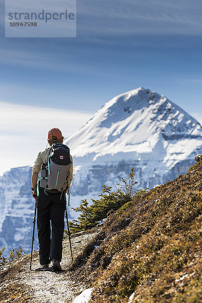 Wanderin mit Stöcken auf einem Bergpfad mit Gletscherspitze in der Ferne  Banff National Park; Alberta  Kanada'.