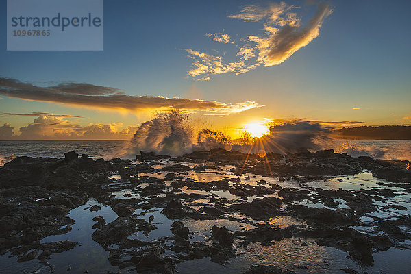 Wellen brechen bei Sonnenaufgang über einen Felsvorsprung; Kauai  Hawaii  Vereinigte Staaten von Amerika'.