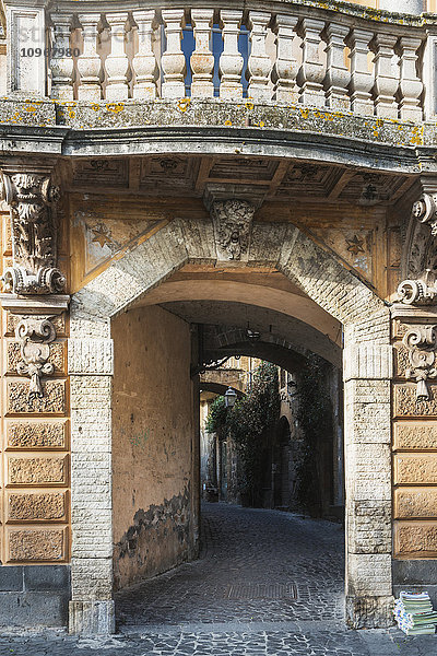 Fassade eines Gebäudes  die zu einem Gehweg führt  mit Balustraden über dem Gebäude; Orvieto  Umbrien  Italien