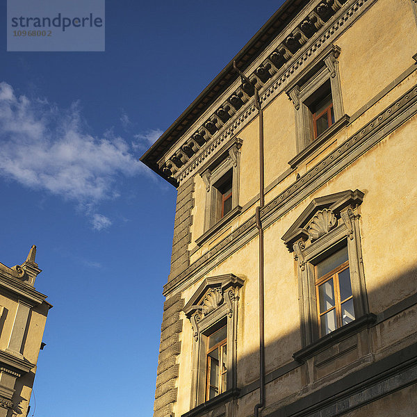 Niedriger Blickwinkel auf die Fassade und die Dachlinie eines gelben Gebäudes und blauer Himmel; Orvieto  Umbrien  Italien
