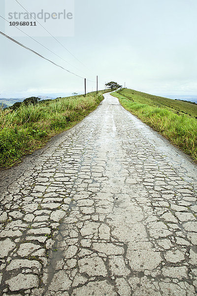 Langansicht einer beschädigten Straße oberhalb eines Berges; Costa Rica'.