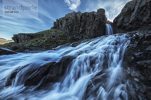 Ein kleiner Wasserfall fließt entlang der Ostküste Islands in den Ozean; Island'.