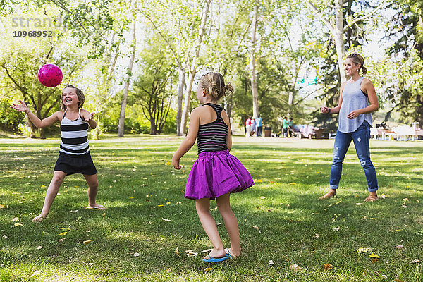 Mutter und Töchter werfen einen Ball in einem Park während eines Familienausflugs; Edmonton  Alberta  Kanada'.