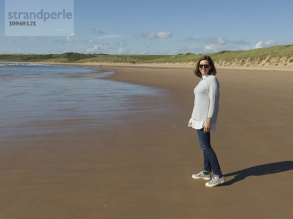 Frau mit Sonnenbrille am Strand von Cruden Bay an der Cruden Bay; Aberdeenshire  Schottland .