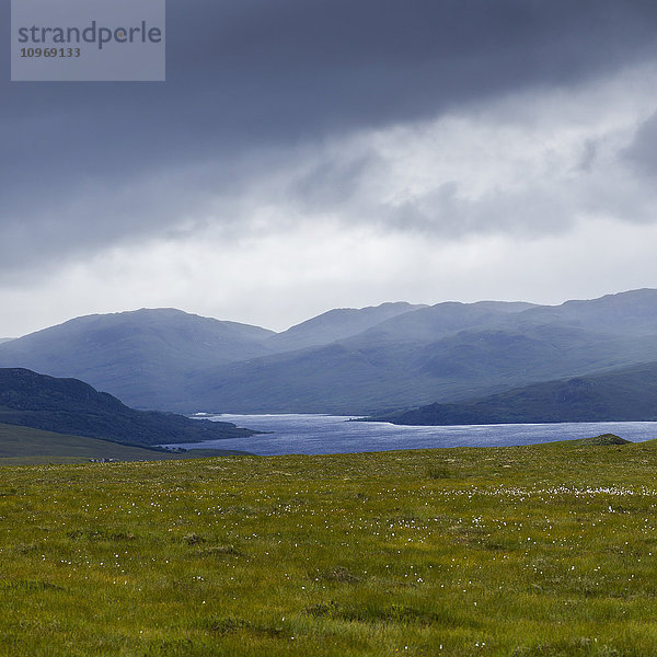 Sturmwolken und Nebel über der bergigen Landschaft und dem Wasser in den schottischen Highlands .
