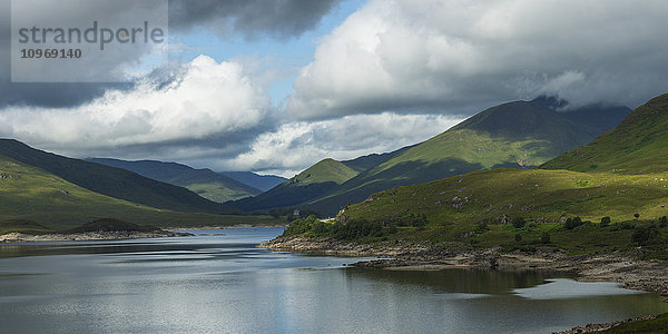 Ruhiges Wasser in einer bergigen Landschaft unter einem bewölkten Himmel; Schottland