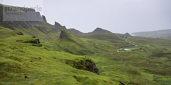 Nebel über der üppig grünen Landschaft mit Klippen und Gipfeln; Staffin  Schottland'.