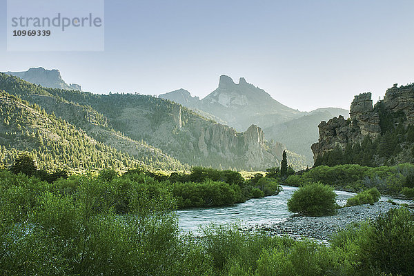 Die frühe Morgensonne beleuchtet ein grünes Flusstal und scharfe Berggipfel; Argentinien .