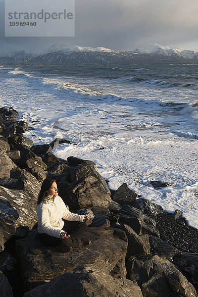 Frau beim Meditieren an einem felsigen Strand  Homer Spit  Southcentral Alaska