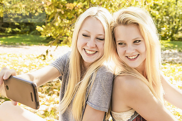 Zwei Schwestern  die im Herbst in einem Stadtpark Spaß haben und ein Selfie machen; Edmonton  Alberta  Kanada'.